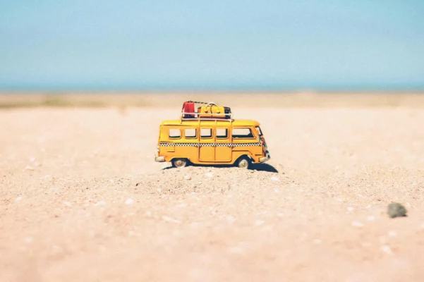 Spielzeug-Reisebus im heißen Sand als Symbol für Medikamente bei Hitze