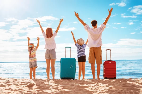 Familie mit Koffern am Strand – Symbolbild für beschwerdefreies Reisen ohne Reiseübelkeit