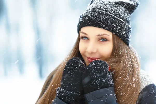 Frau mit warmer Kleidung im Schnee – Hautpflege Winter