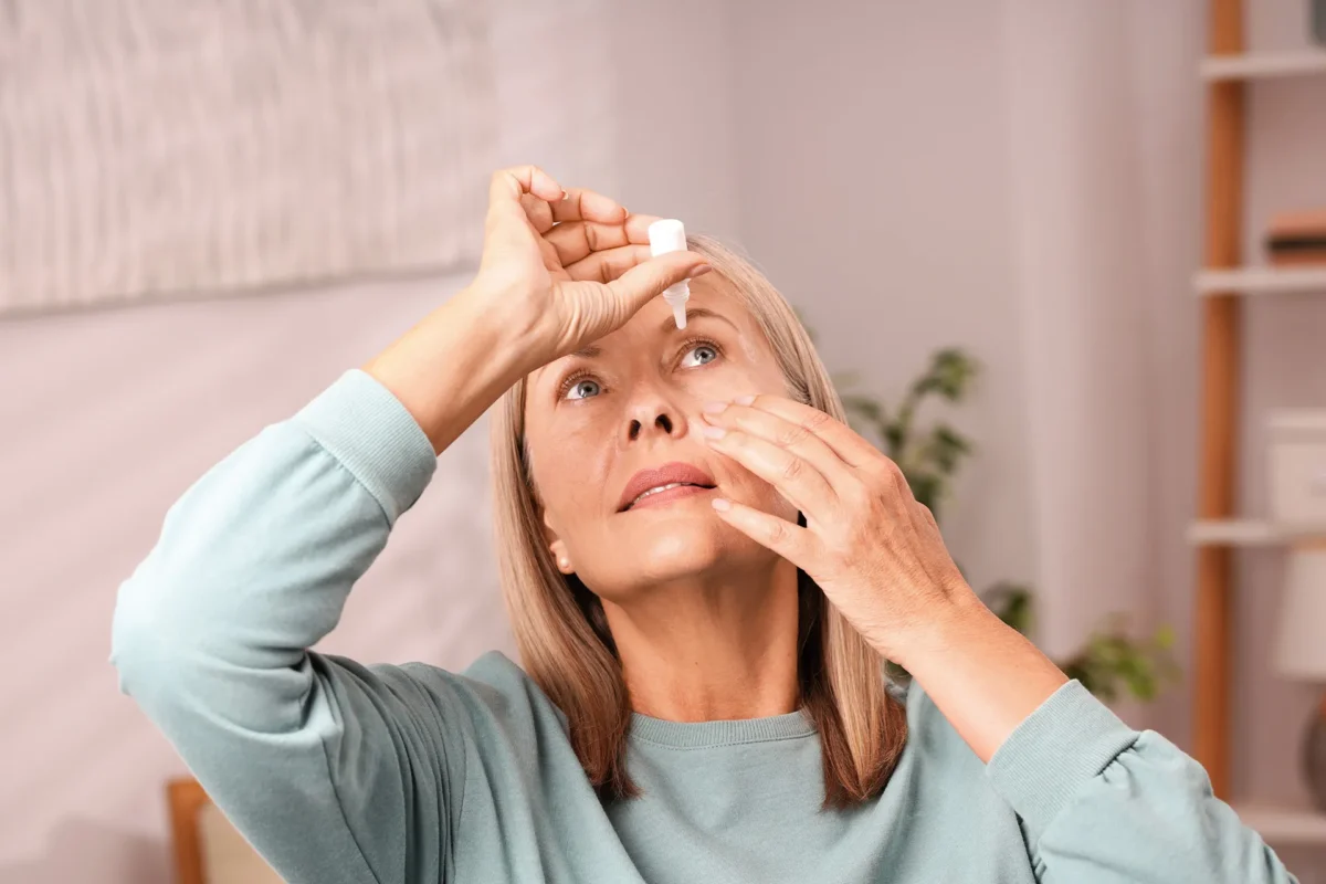 Frau träufelt Augentropfen bei trockenen Augen im Alltag