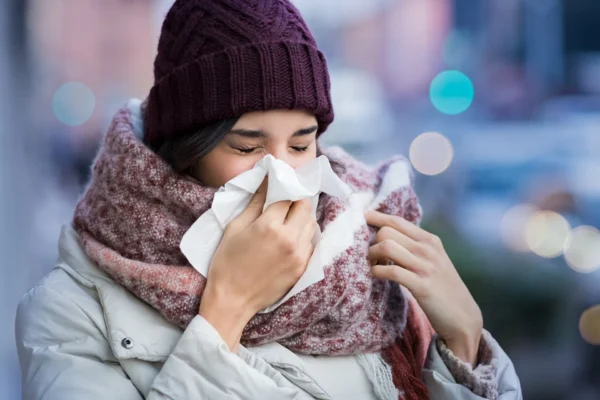 Frau putzt sich im Winter die Nase mit Taschentuch