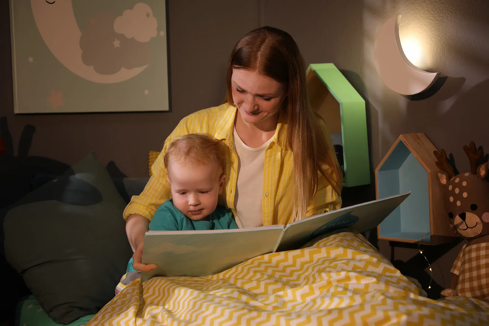 Mutter liest Kleinkind im Bett eine Gute-Nacht-Geschichte bei Schlafprobleme Kinder