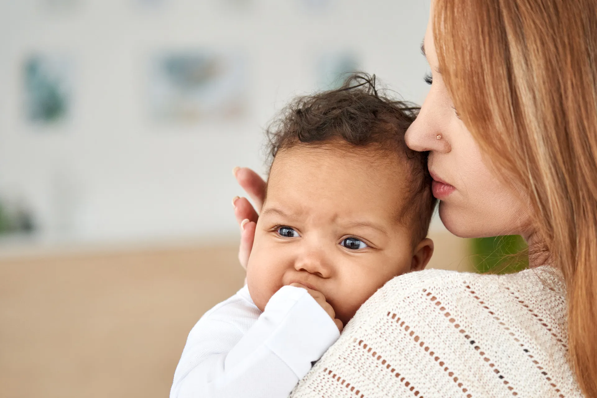 Mutter beruhigt ihr Baby, das beim Zahnen an der Hand kaut – Nähe als sanfte Hilfe